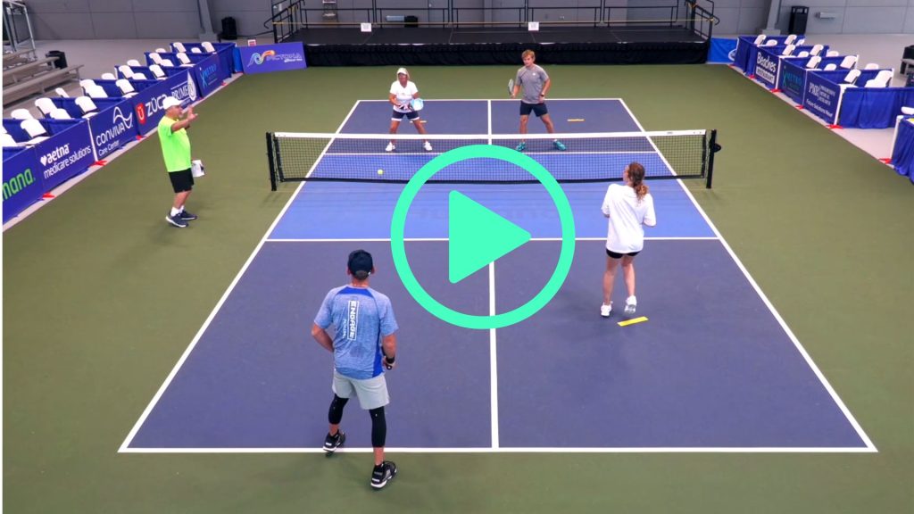 Foursome on a pickleball court with a coach that is instructing them through drills.