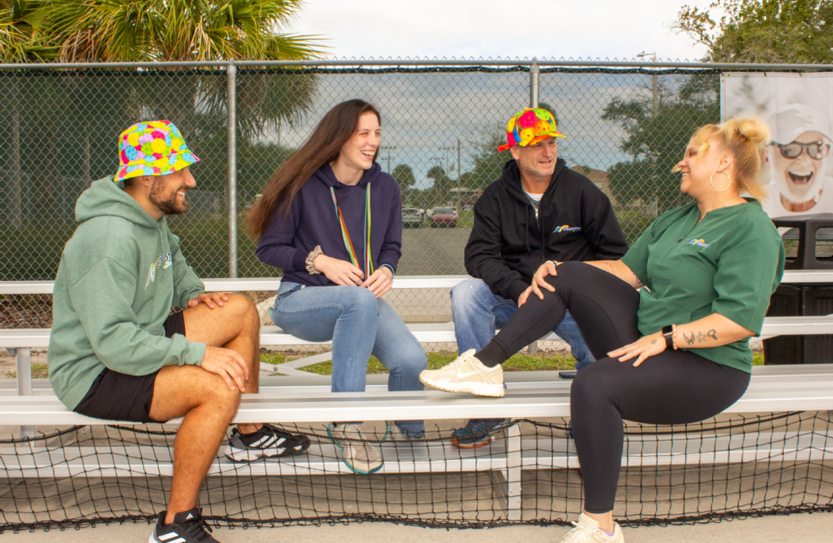 Four young adults sitting on bleachers at Pictona
