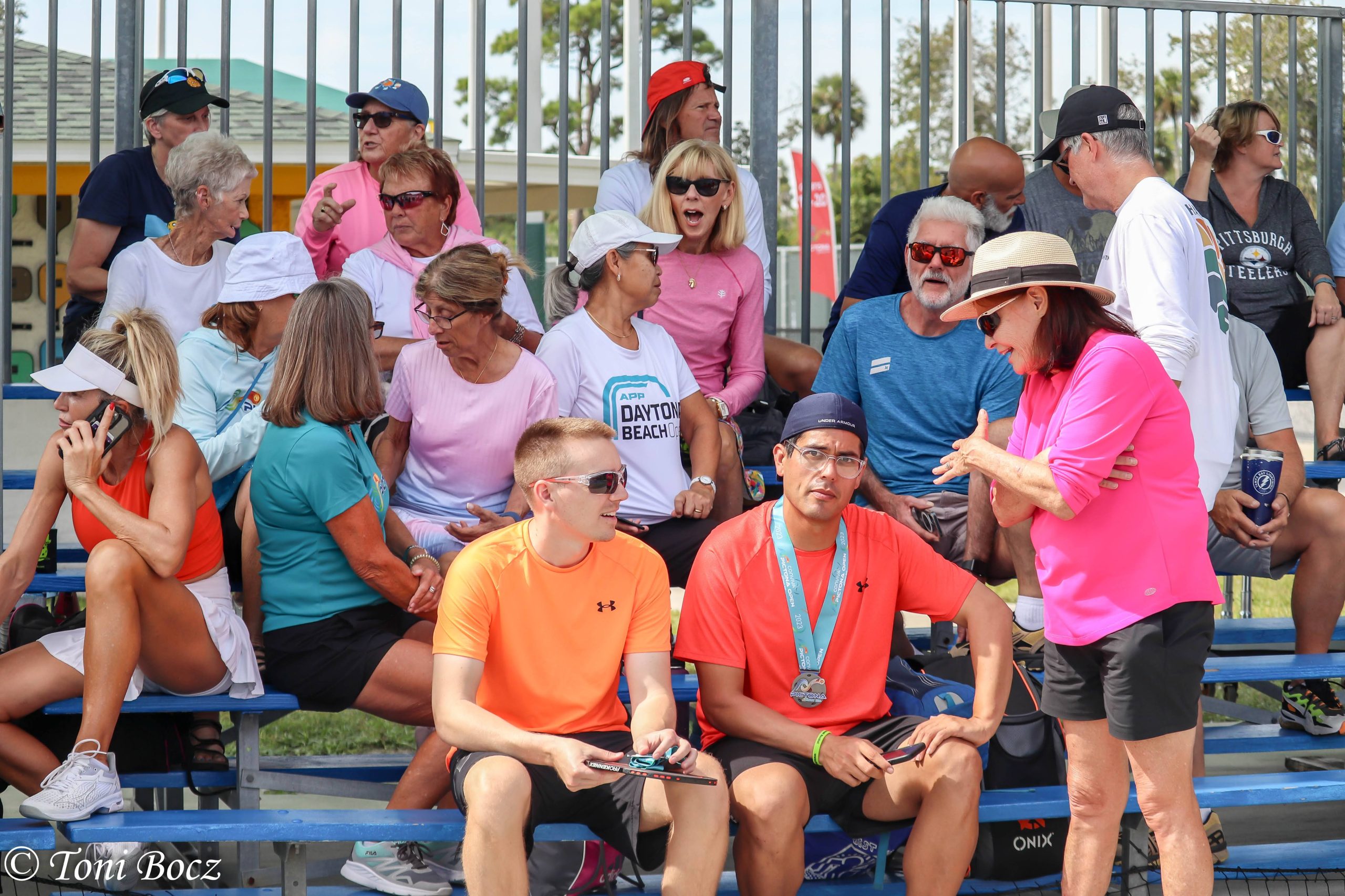 Group of people chatting in the stands of pickleball courts